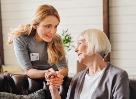 Young caregiver holding a senior woman's hand while listening to her.