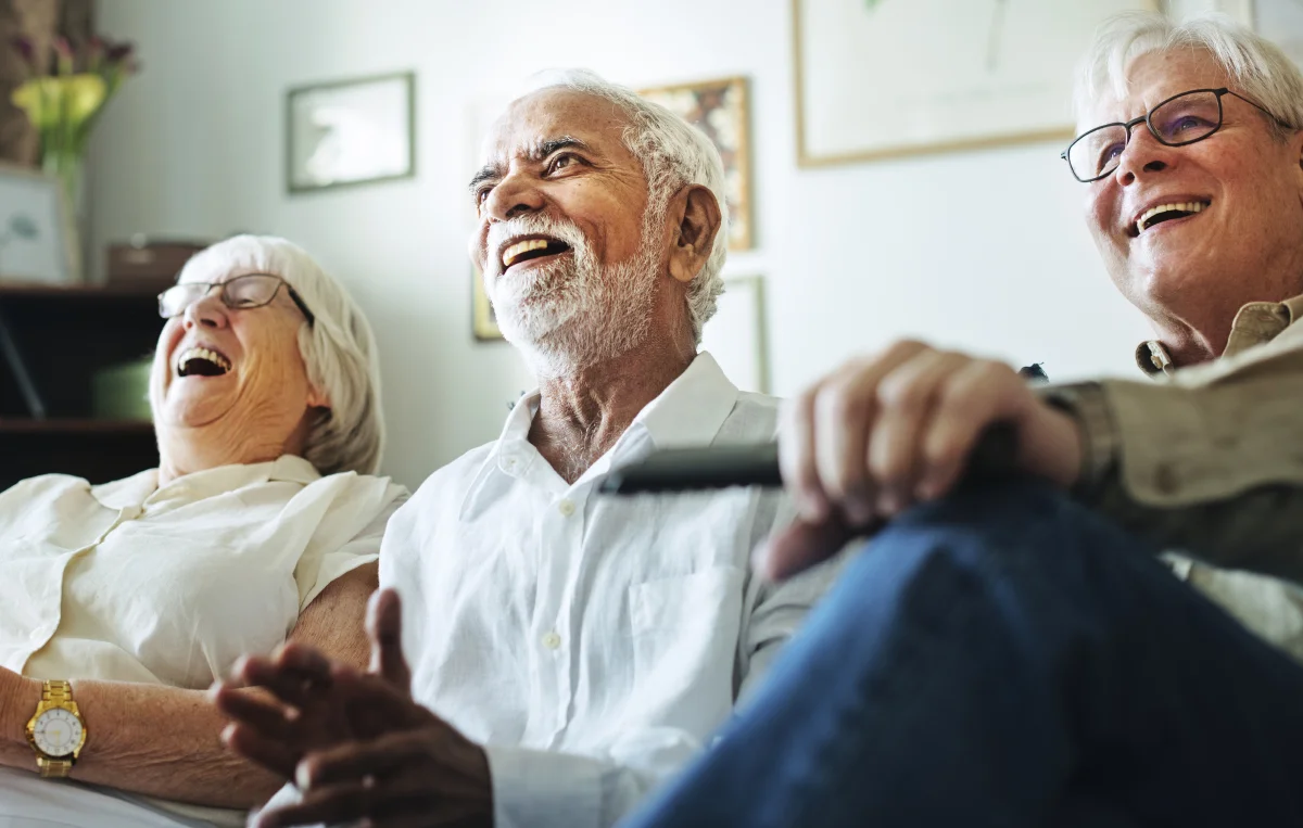 group of senior friends watching television together on couch